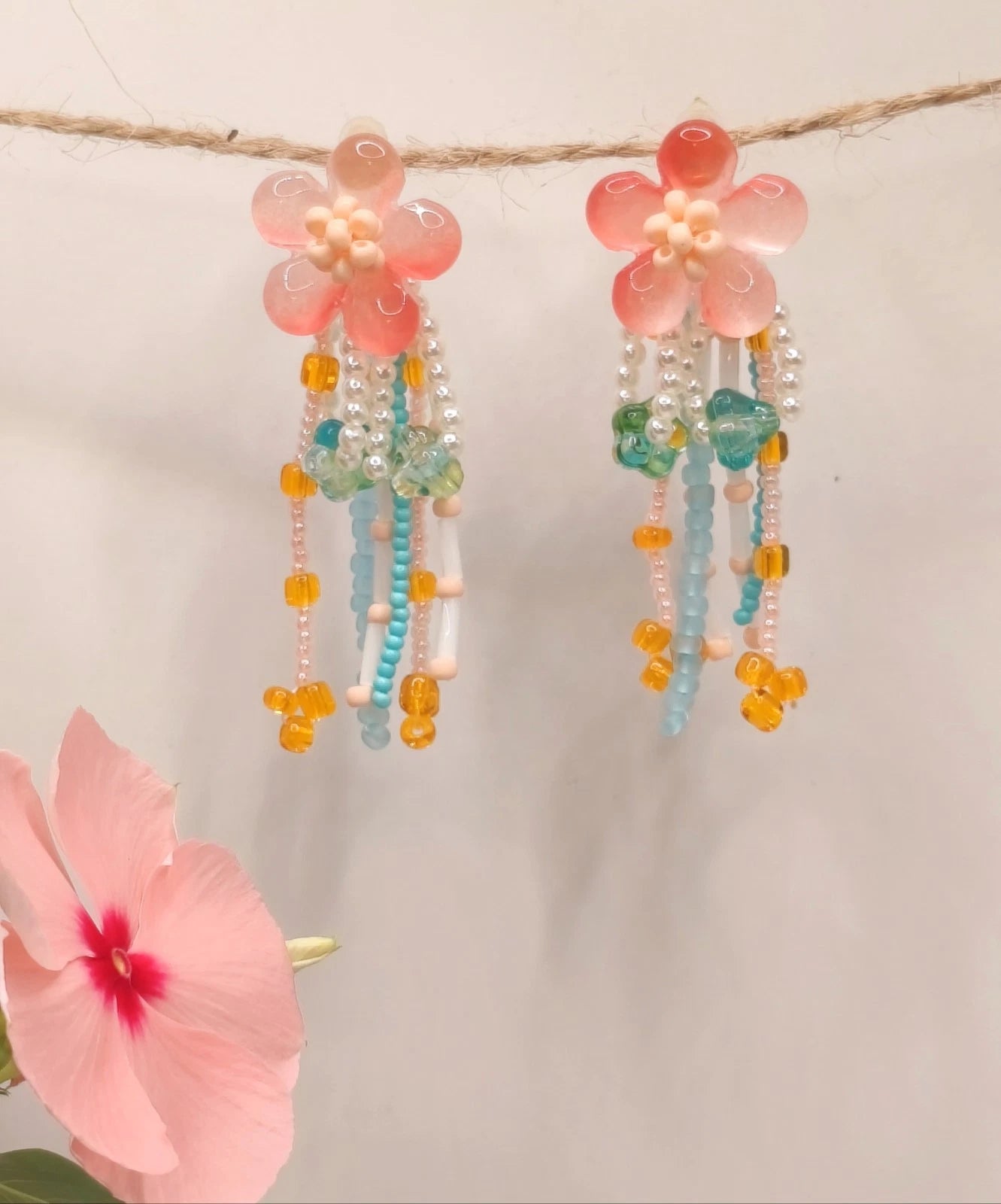 Handgefertigte Ohrringe mit Naturperlen und Kunstharz mit Blumenmotiven und Quasten